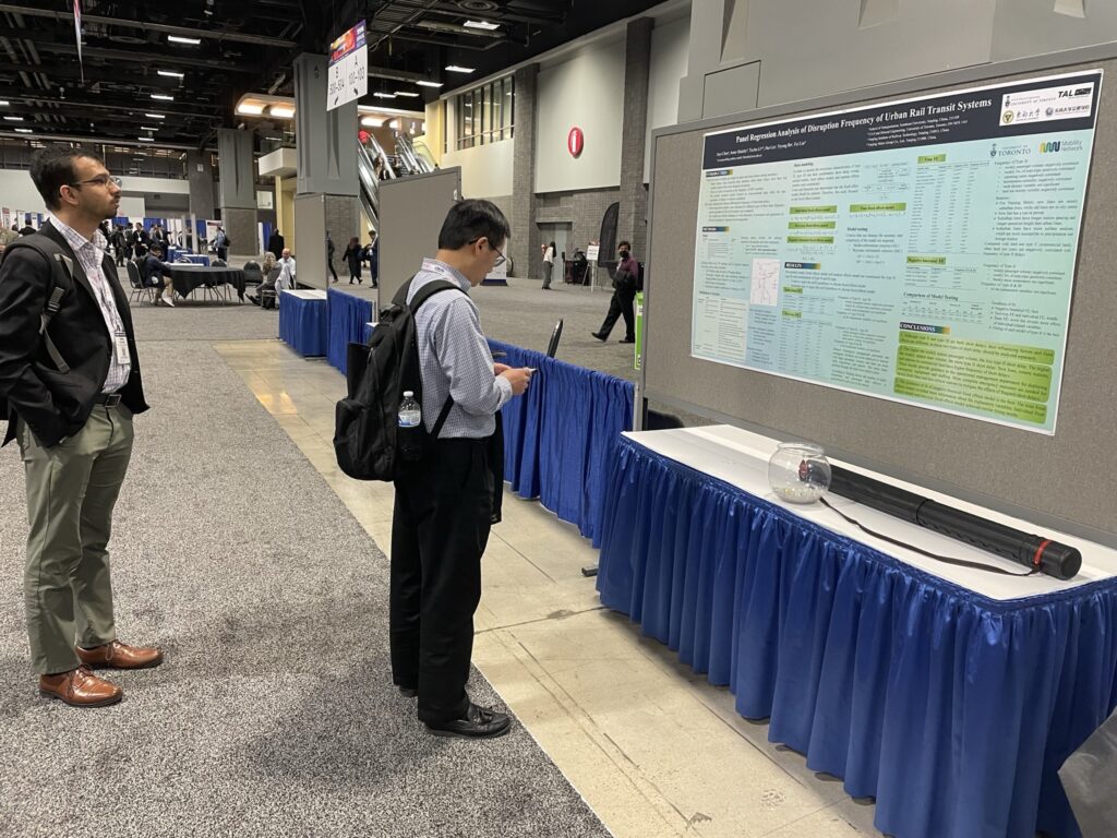 TRB 2023 conference attendees read research poster.